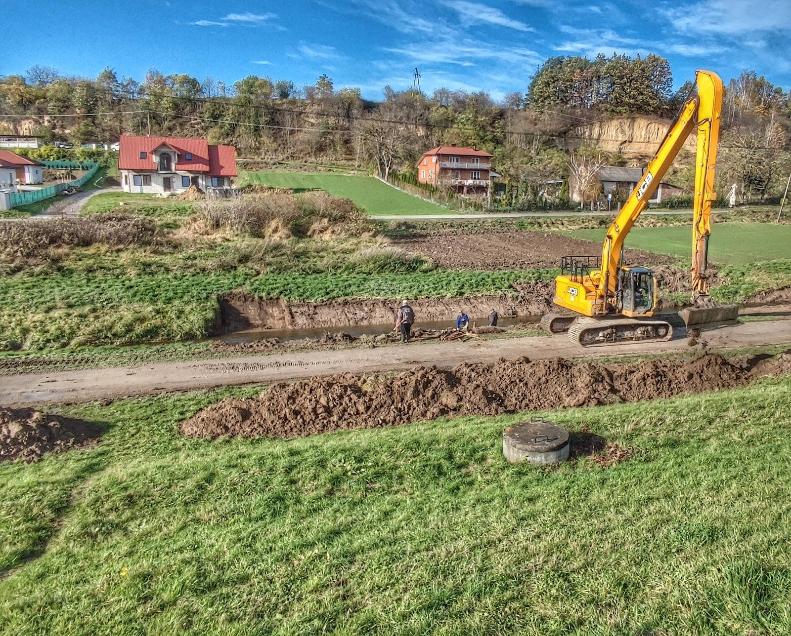 Koparka JCB podczas robót melioracyjnych i profilowania kanału w terenie otwartym